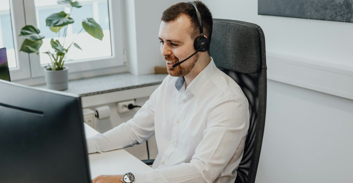 a man wearing a headset sitting in front of a computer