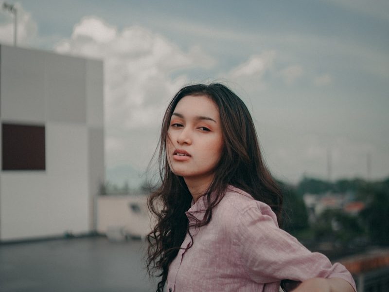 a woman standing on top of a balcony next to a building