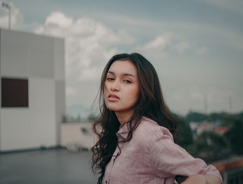 a woman standing on top of a balcony next to a building